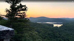 A natural landscape with a body of water, forested hills, and a clear sky.