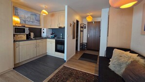 A modern apartment with a kitchen, dining area, and living room. - Cozy studio, centrally located, with mountain views (Saas-Fee)