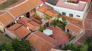 Un patio con techos de tejas tradicionales, muros de piedra y un espacio central abierto con una estructura blanca.