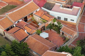 Un patio con techos de tejas tradicionales, muros de piedra y un espacio central abierto con una estructura blanca.