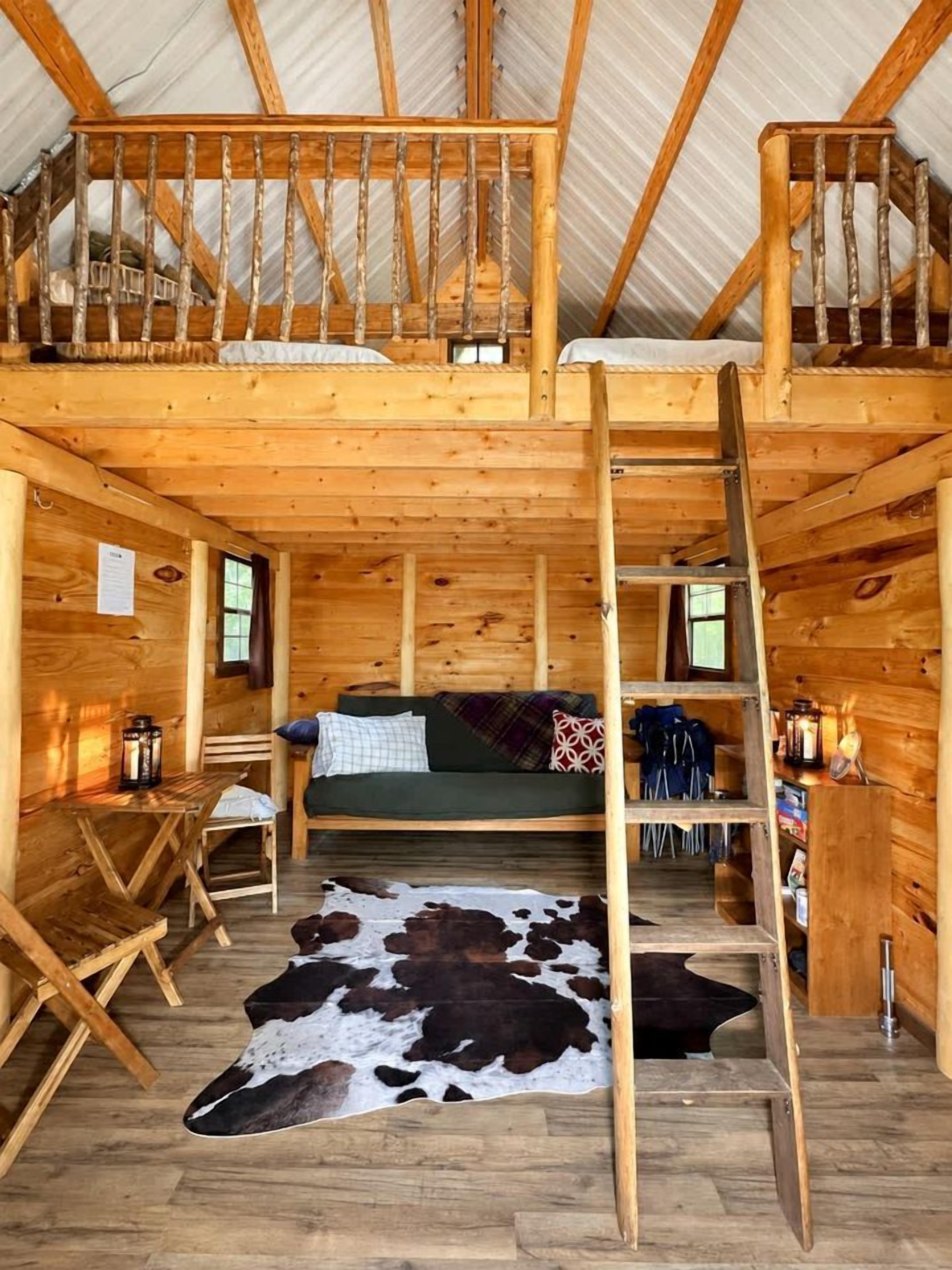 A wooden cabin with a loft bedroom, a dining area, and a living space.