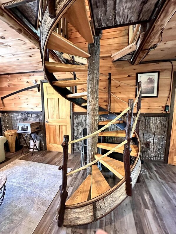 A wooden spiral staircase with a rustic design, leading to an upper level.