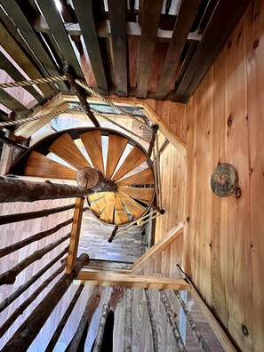 A wooden spiral staircase with a rustic design, leading to an upper floor.