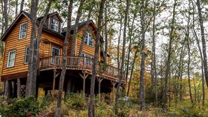 Une cabane en bois dotée d’un balcon, entourée d’arbres.