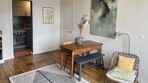 A dining area with a wooden table, bench, and a vase with dried flowers. - Parisian apartment on courtyard (Paris)
