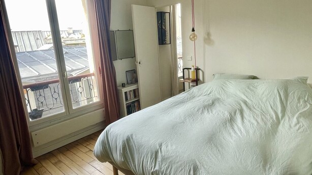 A bedroom with a bed, a wardrobe, a desk with a chair, and a window with curtains. - Parisian apartment on courtyard (Paris)