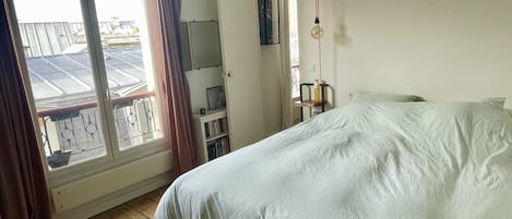 Une chambre à coucher comprenant un lit, une armoire, un bureau avec une chaise et une fenêtre avec des rideaux.