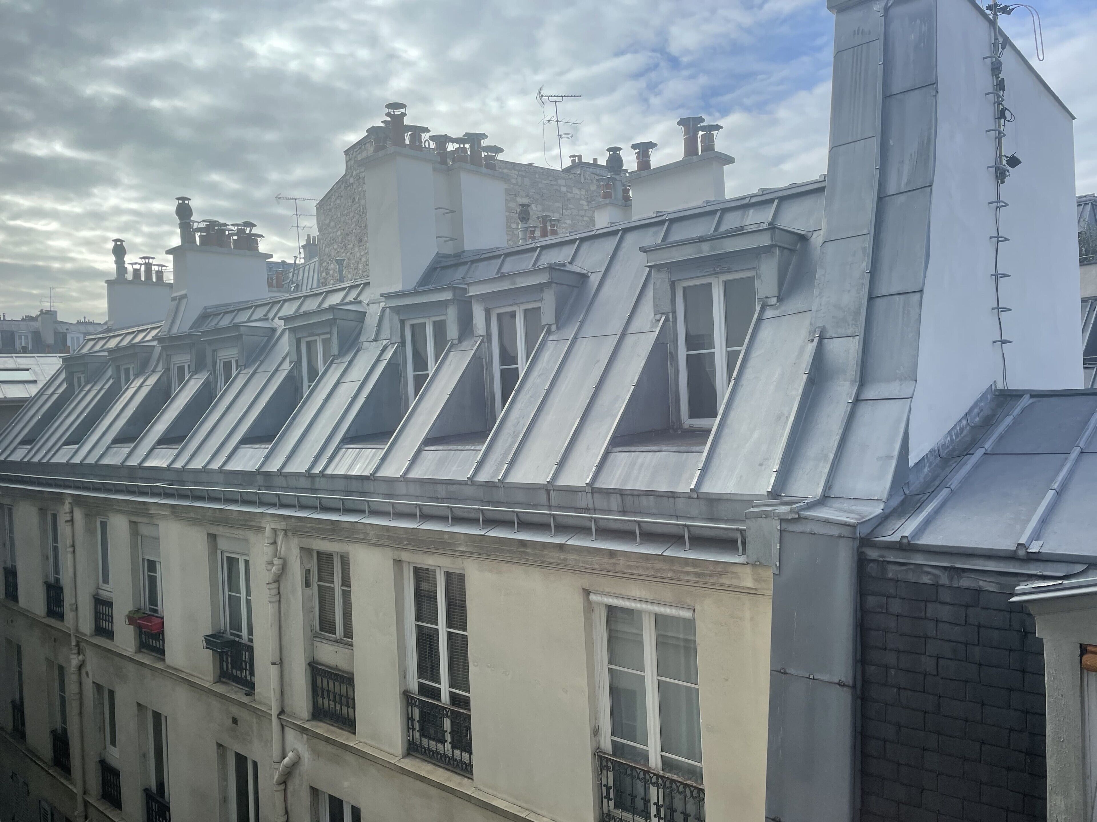A row of residential buildings with multiple roof levels, including dormer windows and chimneys.