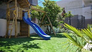 A wooden play structure with a blue slide in a backyard with artificial grass and a tree. - Luxury Villa Blu with pool by the beach (Okrug Gornji)