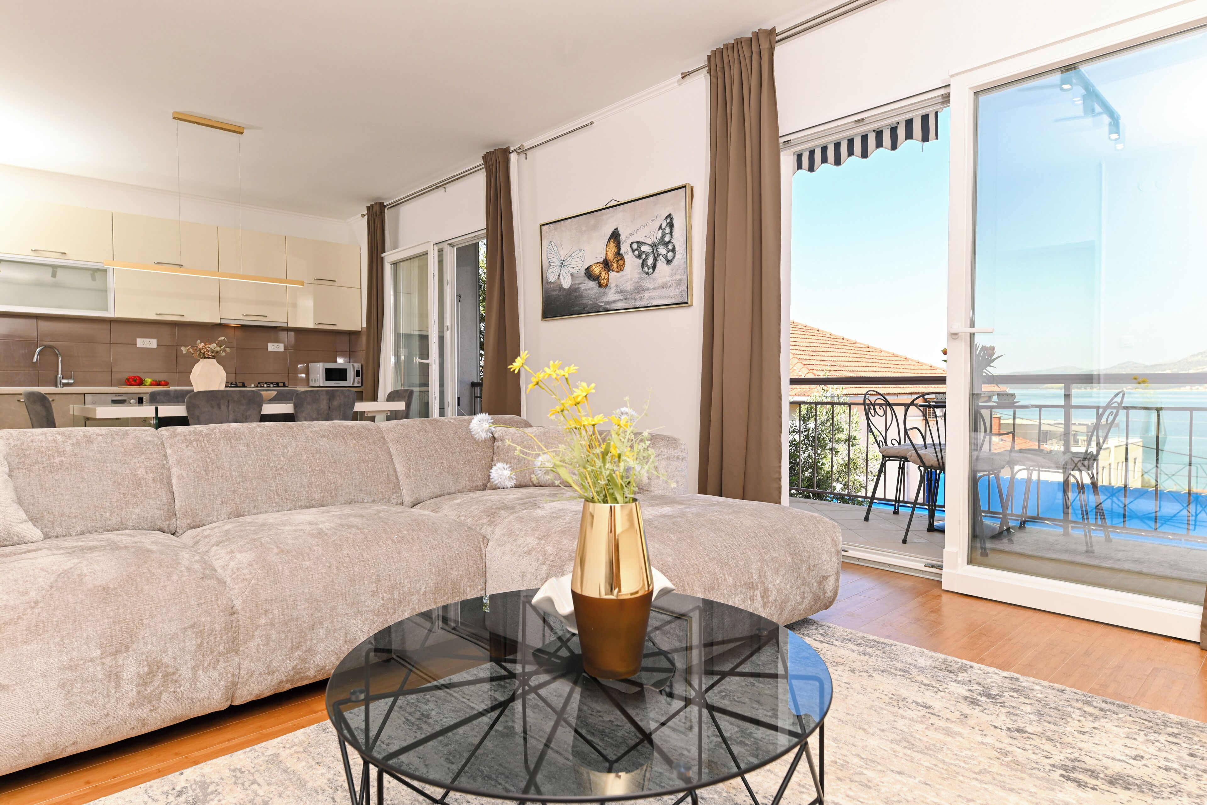 Ein modernes Wohnzimmer mit einem Ecksofa, einem Glastisch und einem Balkon mit Blick.