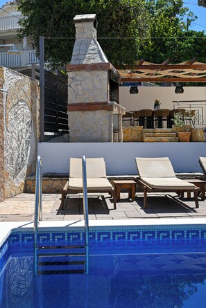 A swimming pool with lounge chairs and a stone wall. - Luxury Villa Blu with pool by the beach (Okrug Gornji)