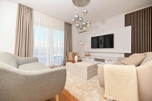A modern living room with a sofa, a coffee table, and a TV mounted on the wall. - Luxury Villa Blu with pool by the beach (Okrug Gornji)