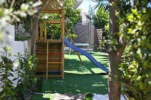 A wooden play structure with a slide and climbing elements, surrounded by green grass and trees. - Luxury Villa Blu with pool by the beach (Okrug Gornji)