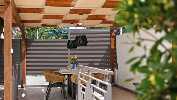 An outdoor patio with a table and chairs, a hanging light fixture, and a wall-mounted shoe rack. - Luxury Villa Blu with pool by the beach (Okrug Gornji)