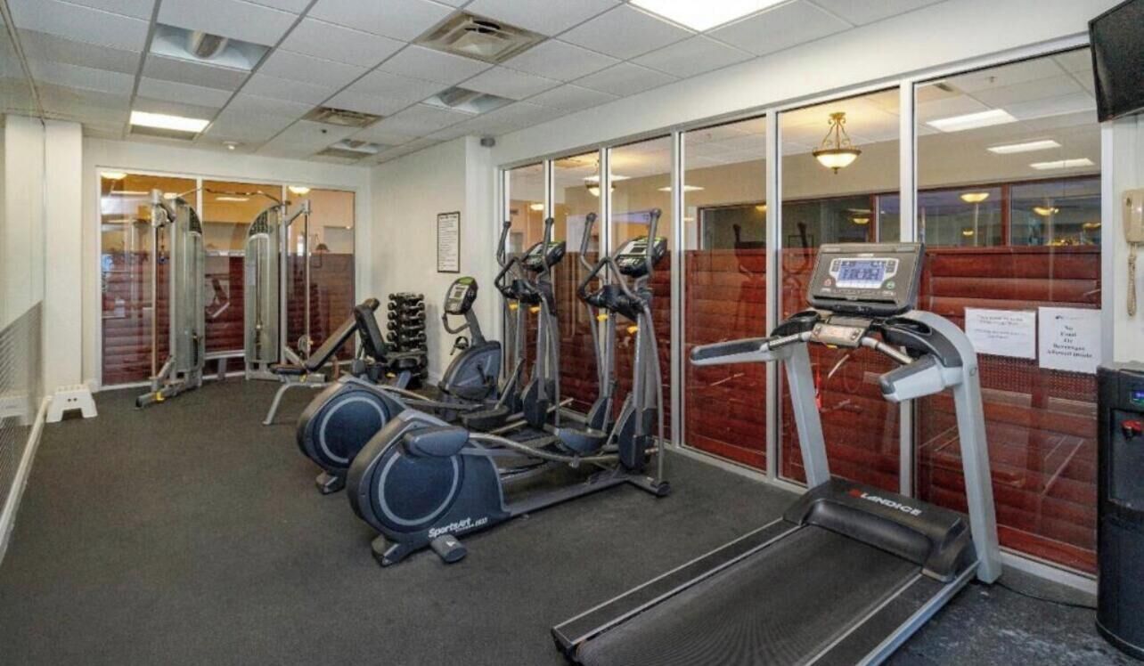 Ein Fitnessstudio mit verschiedenen Cardiogeräten, darunter Laufbänder und Crosstrainer.