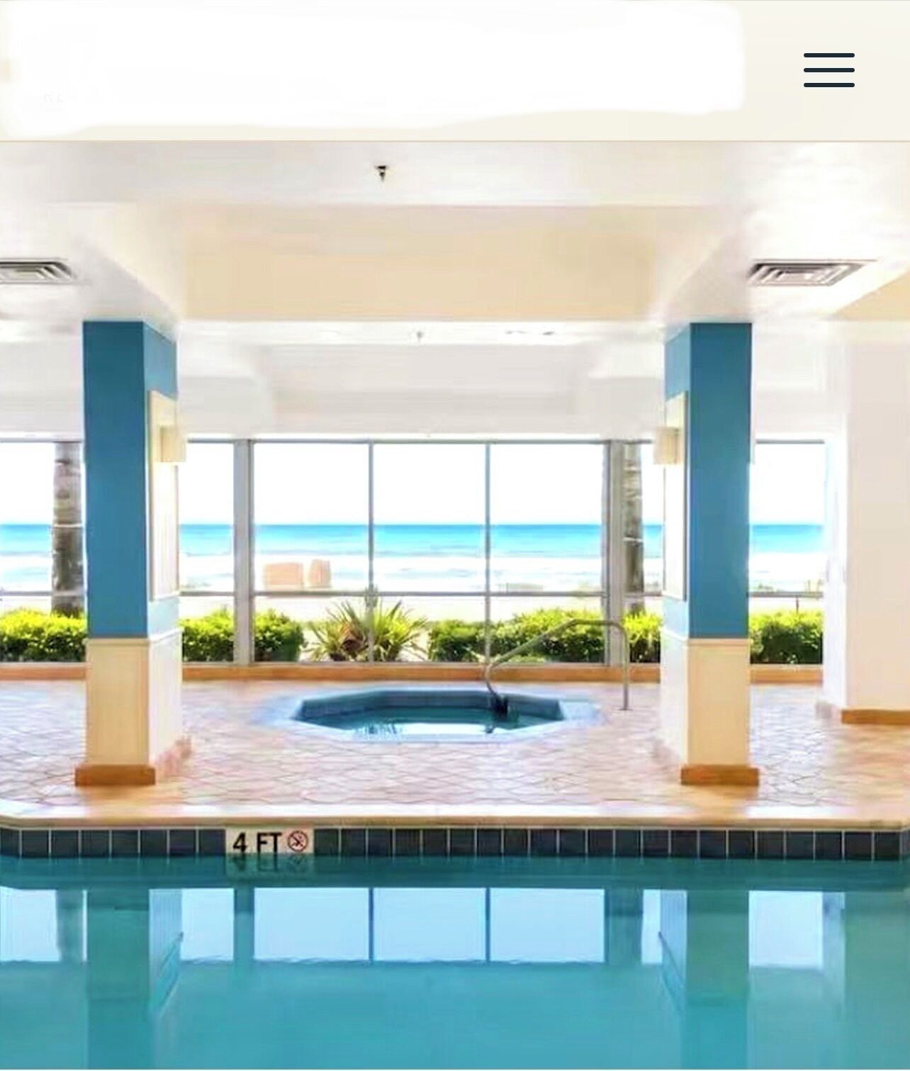 A pool area with a hot tub, large windows, and a view of the ocean.