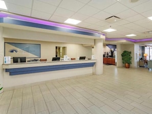 A reception desk with a blue accent, a framed logo, and a potted plant in the background. - Ocean Breeze Daytona Beach Rentals  (Daytona Beach)