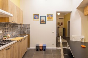 A kitchen with a stove, sink, and tiled backsplash. There are stools and a table with chairs. - Cozy Mini Suite in a quiet neighborhood right in the heart of Palermo's historic center (Palermo)