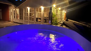 A swimming pool with a blue light, a building with large windows, and a person standing by the pool. - Wellness Center for 20 People—Spa, Sauna, and Activity Room (Hemmet)