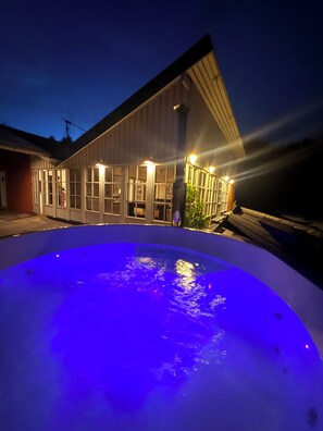 Ein Swimmingpool mit blauem Licht, ein Gebäude mit großen Fenstern und eine Person am Pool.