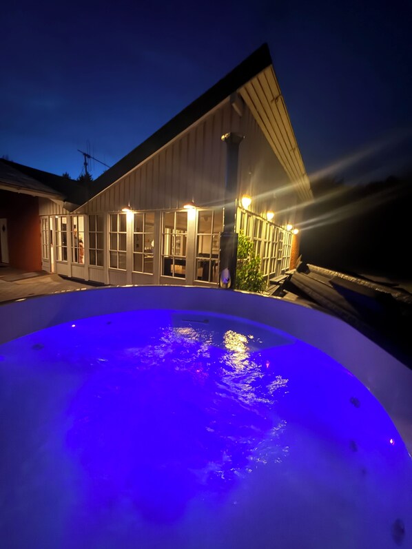 En swimmingpool med blå belysning, en bygning med store vinduer, og en person som står ved poolen.