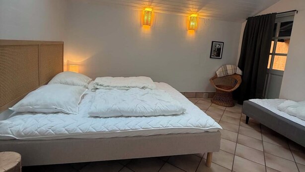 A bedroom with a large bed, a small table, a chair, and two wall-mounted lights. - Wellness Center for 20 People—Spa, Sauna, and Activity Room (Hemmet)