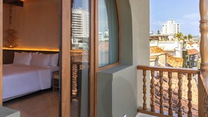 Une chambre d’hôtel avec un lit, une balustrade en bois et une vue sur le paysage urbain.