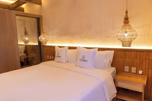 A hotel room with a large bed, two bedside tables, and a wooden headboard.