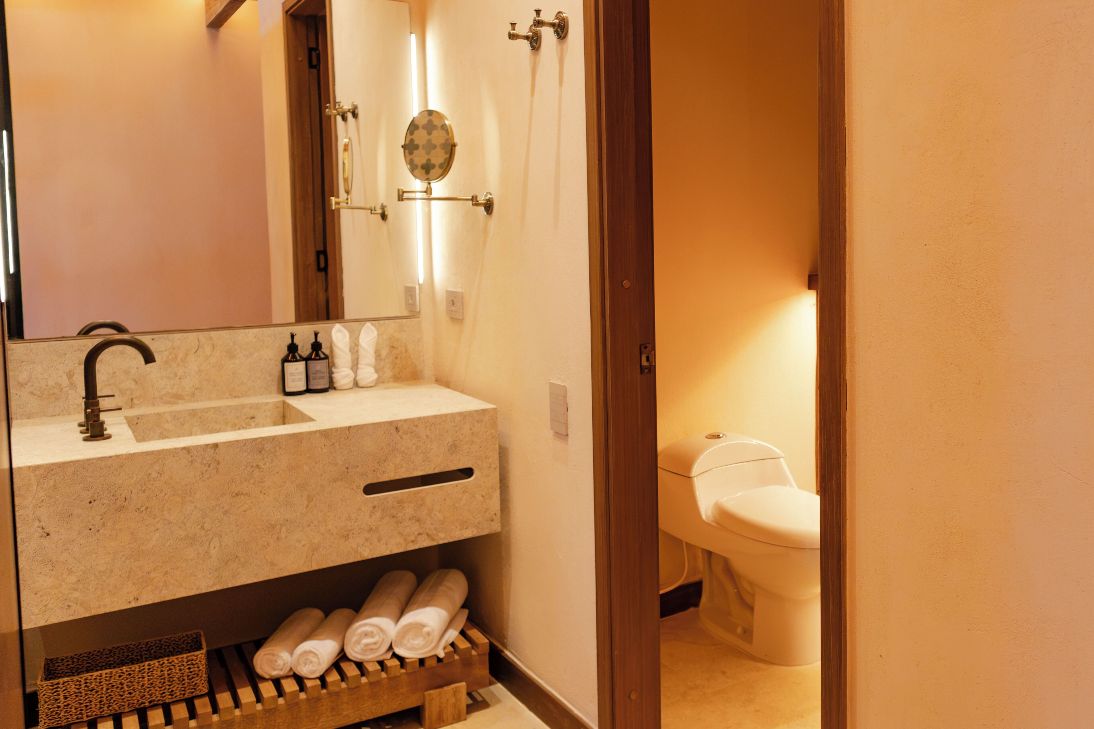 A bathroom with a sink, mirror, towel rack, and toilet.