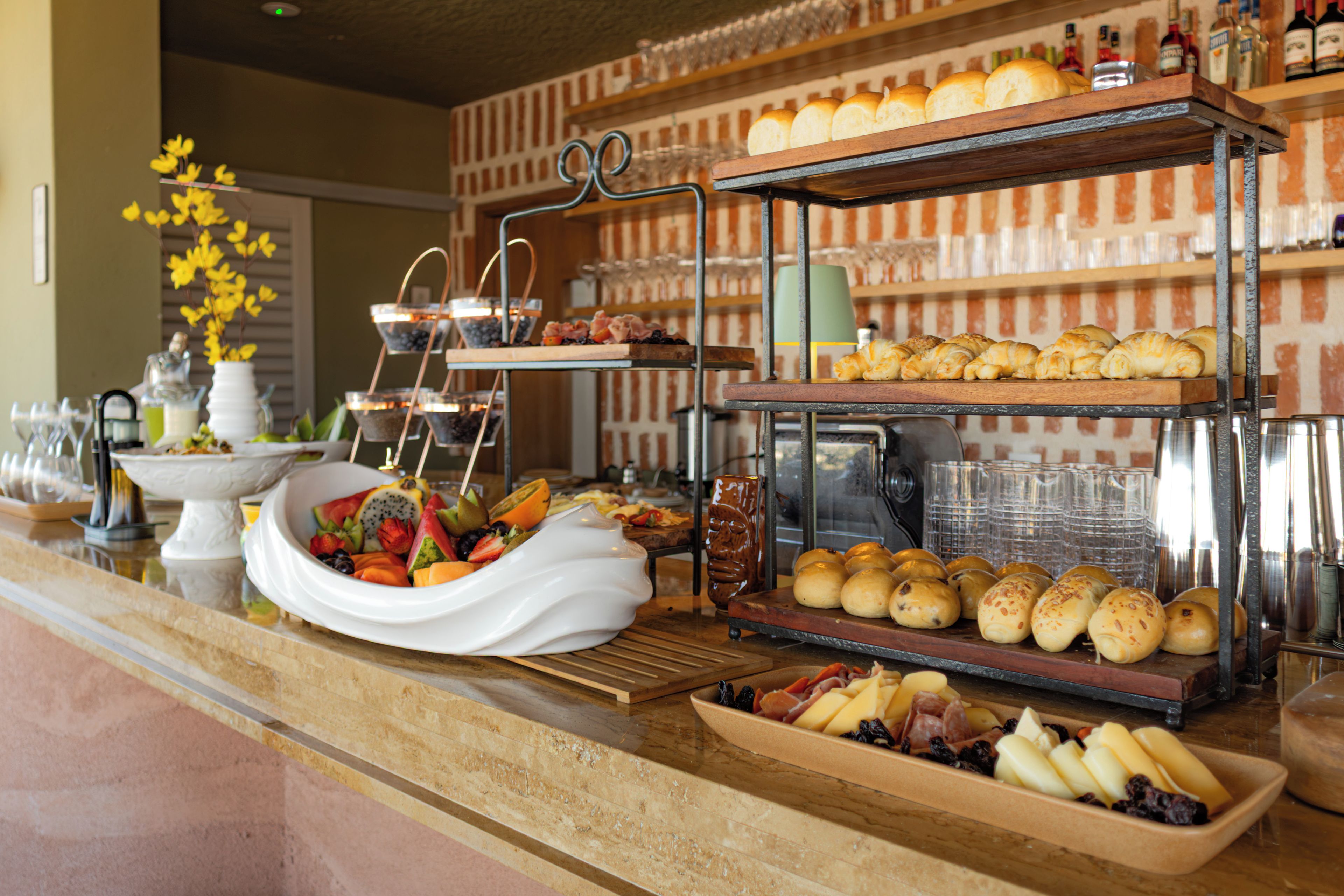 A buffet counter with various food items, including pastries, fruits, and cheeses.