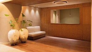 Un intérieur moderne avec un plancher en bois, un canapé blanc et deux grands vases ornés de plantes.