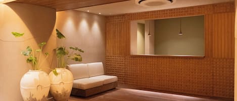 A modern interior with a wooden floor, a white sofa, and two large vases with plants.