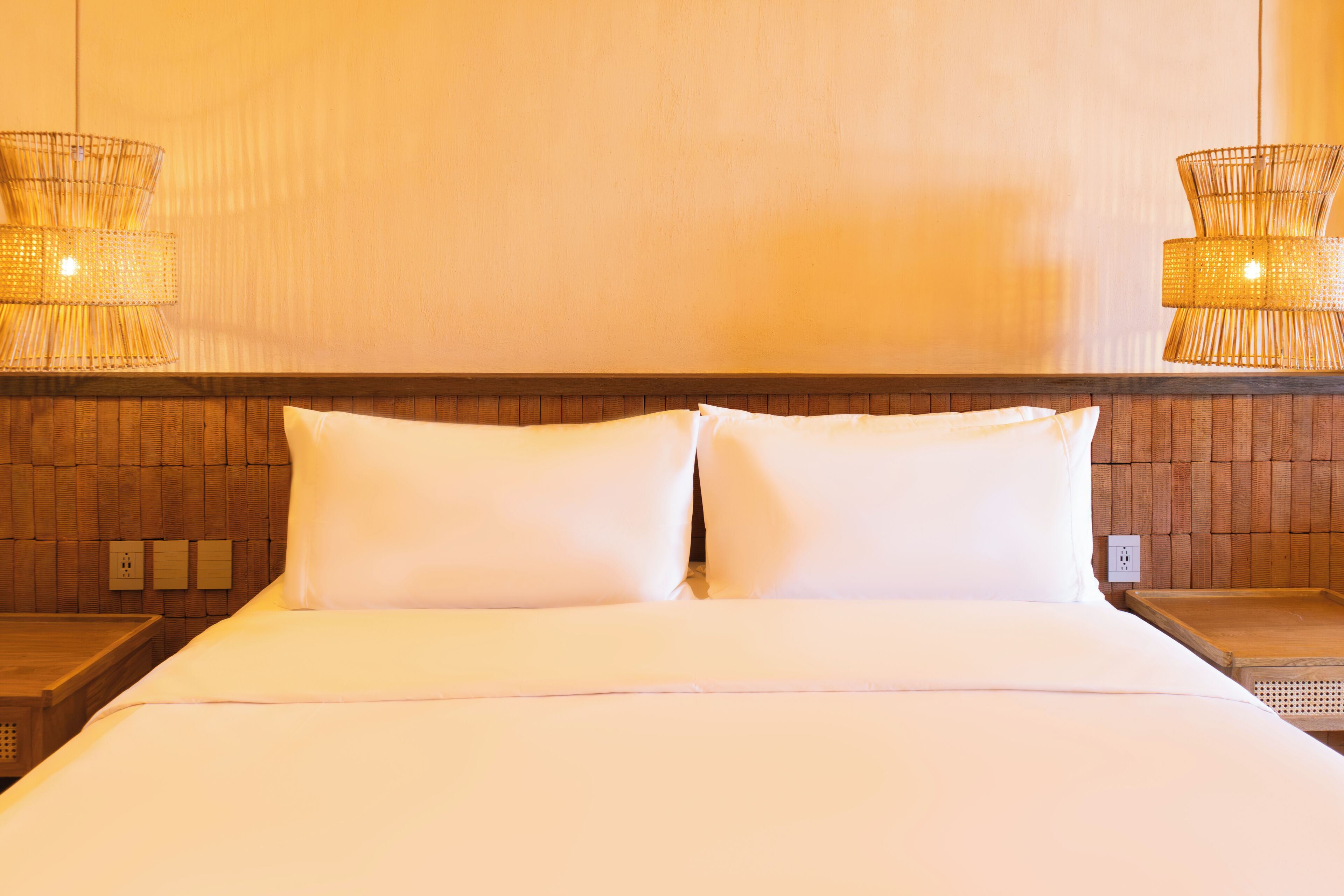 A hotel room with a large bed, two nightstands, and two wall-mounted lamps.