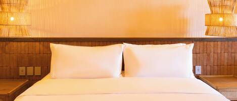 A hotel room with a large bed, two nightstands, and two wall-mounted lamps.
