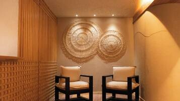Una habitación con dos sillas, una pared con textura e iluminación en el techo.