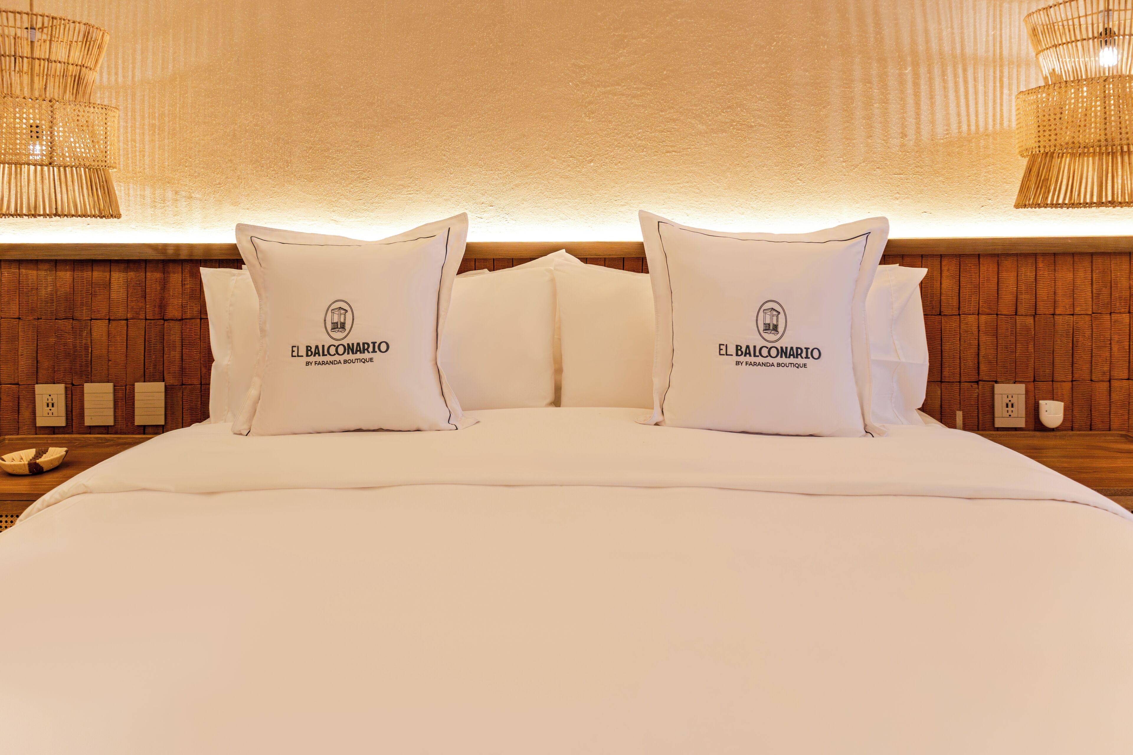 A neatly made bed with white bedding and pillows, each featuring a logo and text.