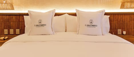 Un lit bien fait, avec une literie blanche et des oreillers, chacun orné d’un logo et d’un texte.