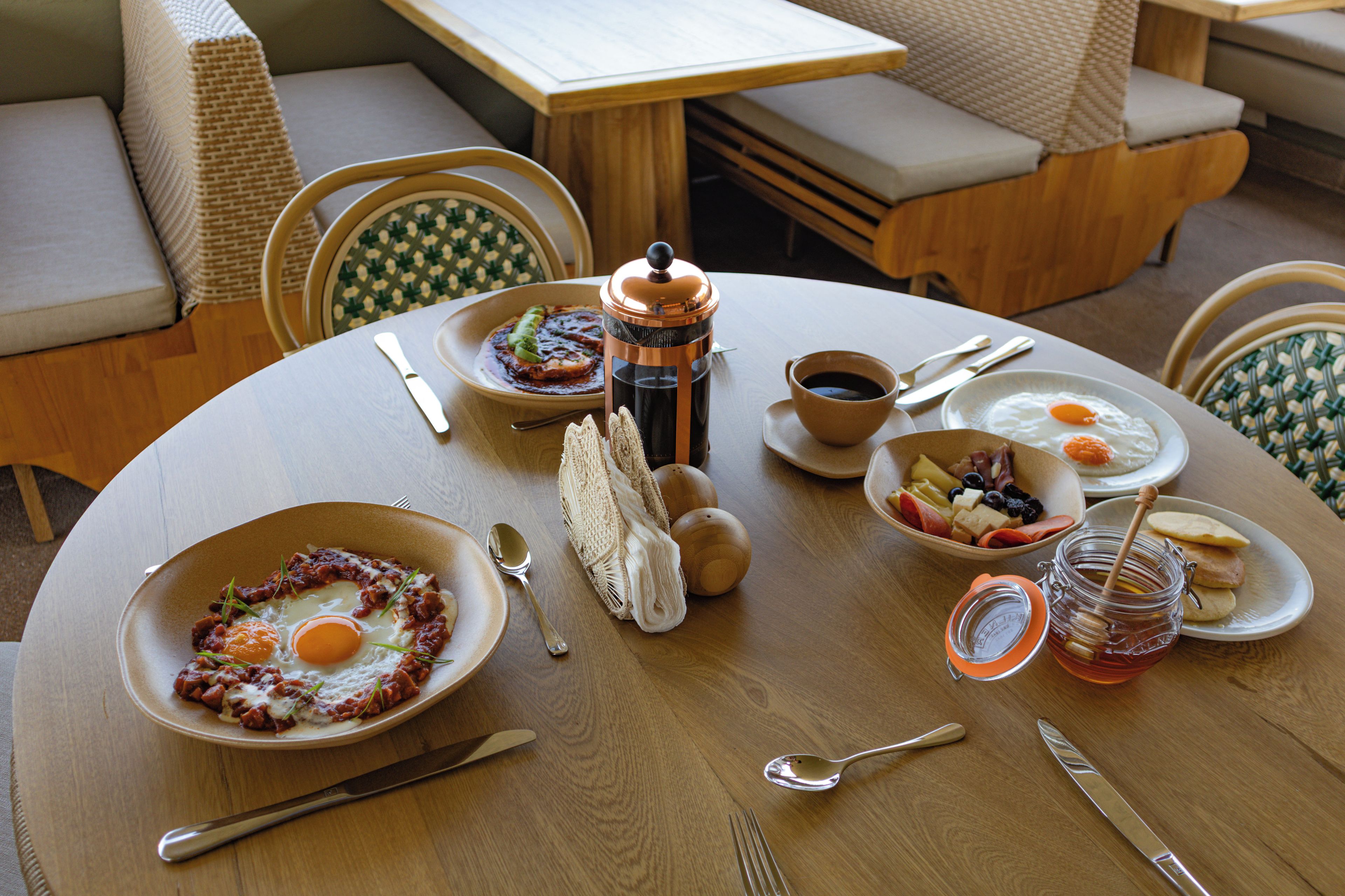 A round dining table with breakfast items, including eggs, toast, and a coffee pot.