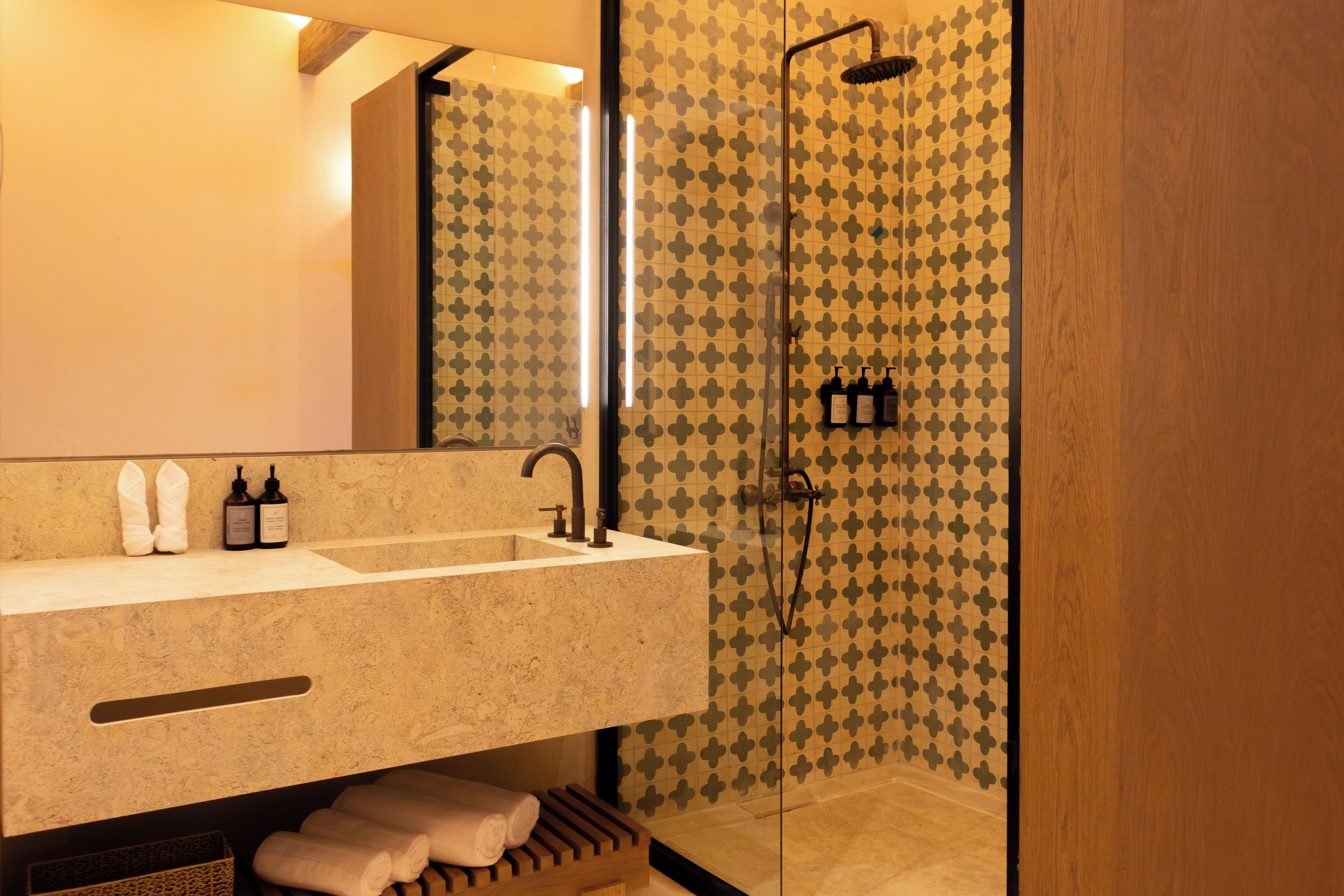A bathroom with a large mirror, a sink, and a shower area.