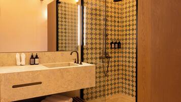 A bathroom with a large mirror, a sink, and a shower area.