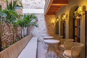 A patio area with wicker furniture, stone walls, and wall-mounted lighting.