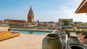 Un espace aménagé au bord de la piscine offrant une vue sur un bâtiment historique et sur le paysage urbain.