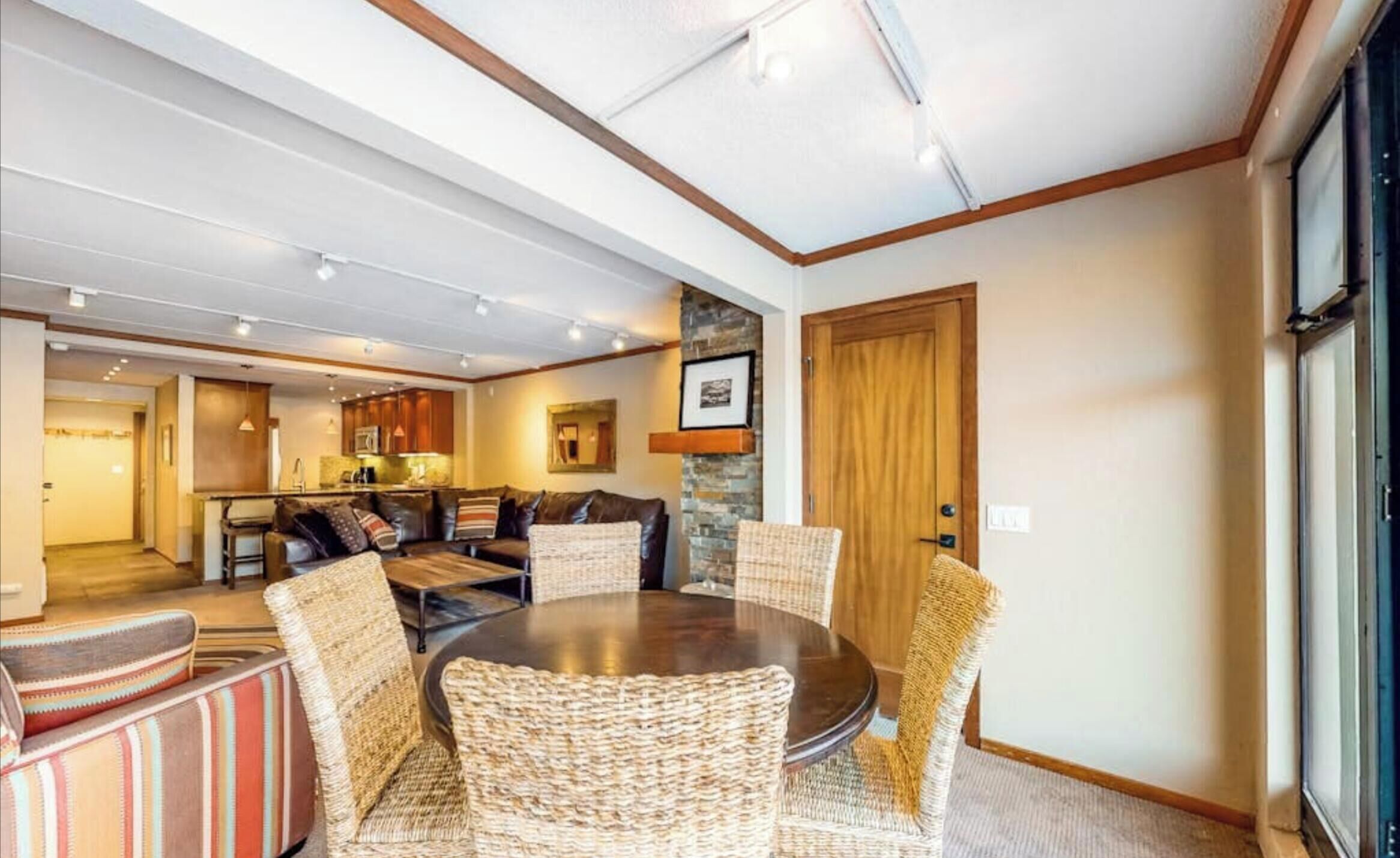 Un coin repas avec une table ronde, des chaises en osier et un mur décoratif en pierre.