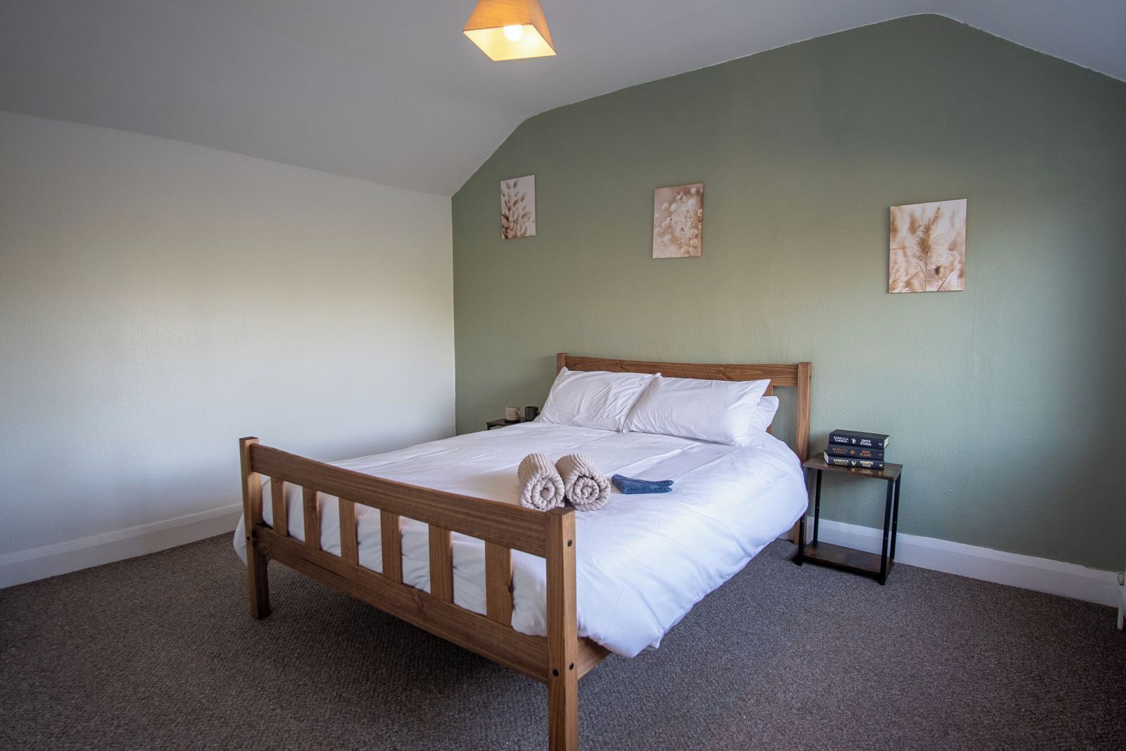 A bedroom with a wooden bed, a nightstand, and wall art.