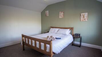 A bedroom with a wooden bed, a nightstand, and wall art.