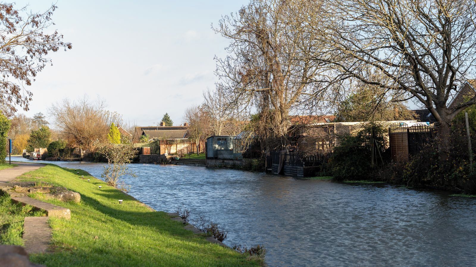 A river with a lock system, a grassy bank, and buildings in the background.