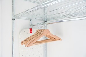 A metal shelving unit with wooden hangers. - GuestReady - House of Many Faces - Room 1 (Porto)