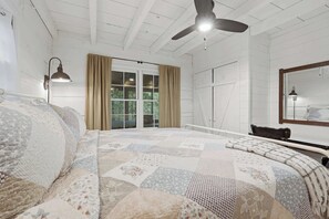A bedroom with a large bed, a ceiling fan, a window with curtains, and a nightstand with a lamp. - Peace of Aska - Hot Tub (Blue Ridge)