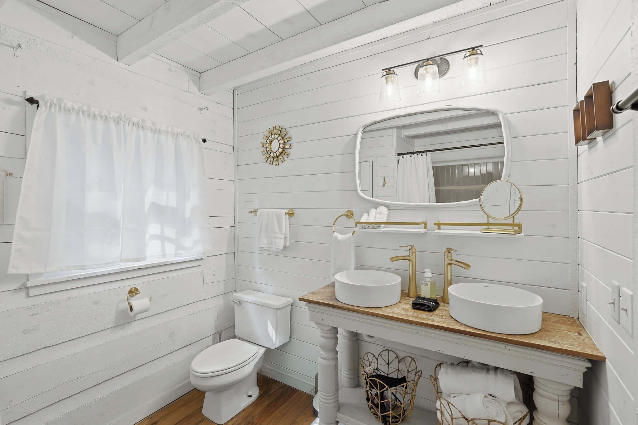 A bathroom with a white toilet, a sink with a mirror above it, and a shower curtain.