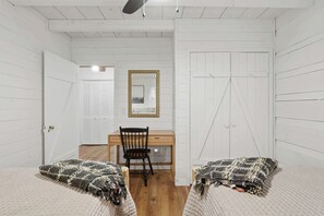 Ein Zimmer mit zwei Betten, einem Schreibtisch, einem Stuhl und einem Spiegel an der Wand.